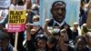 Из фотоархива: одна из многих демонстраций, проведённых в США, Великобритании и других странах — против полицейской жестокости и дискриминации чернокожих. Протестующие держат над головами портрет Джорджа Флойда