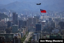 A Taiwanese flag is carried by a Chinook helicopter during a rehearsal for the upcoming National Day celebration in Taipei in October 2021.