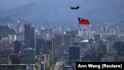 Un steag taiwanez este purtat de un elicopter Chinook în timpul unei repetiții pentru celebrarea Zilei Naționale a insulei, la Taipei, pe 7 octombrie.