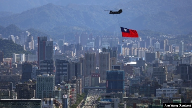 Un steag taiwanez este purtat de un elicopter Chinook în timpul unei repetiții pentru celebrarea Zilei Naționale a insulei, la Taipei, pe 7 octombrie.