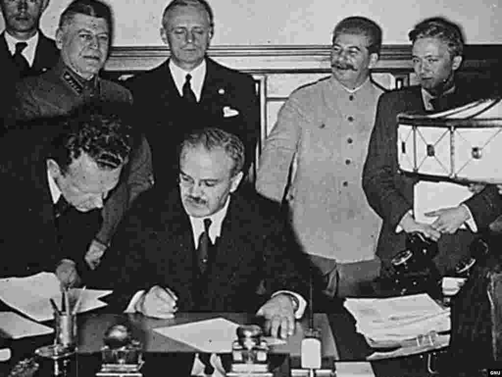 Ministrul de externe Viaceslav Molotov semnează pactul de neagresiune ruso-german. Moscova 23 august 1939. În spate se află Ribbentrop și Stalin.&nbsp;