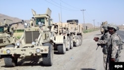 U.S. soldiers inspect the scene of a suicide car bomb attack in Kandahar in May.