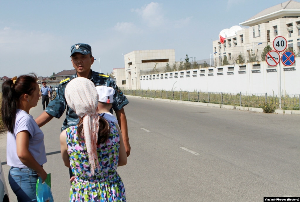 A member of Kyrgyz security forces addresses passersby near the site of a bomb blast outside China's embassy in Bishkek on August 30, 2016.