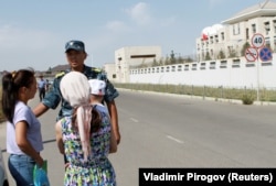 Сотрудник сил безопасности Кыргызстана просит прохожих не приближаться к месту взрыва бомбы у посольства Китая в Бишкеке, 30 августа 2016 года