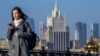 A woman looks at her phone as she walks across a bridge with the Russian Foreign Ministry building in the background, in central Moscow. (file photo)