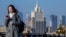 A woman looks at her phone as she walks across a bridge with the Russian Foreign Ministry building in the background, in central Moscow. (file photo)