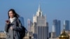 Жена гледа телефона си, докато върви по мост в центъра на Москва, на фона на сградата на руското външно министерство (илюстративна снимка).