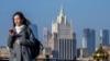 RUSSIA -- A woman looks at her phone as she walks across a bridge with the Russian Foreign Ministry building in the background, in central Moscow, on October 12, 2021.