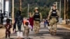 Military police walk past Afghan refugees at the Ft. McCoy U.S. Army base in Wisconsin in September.