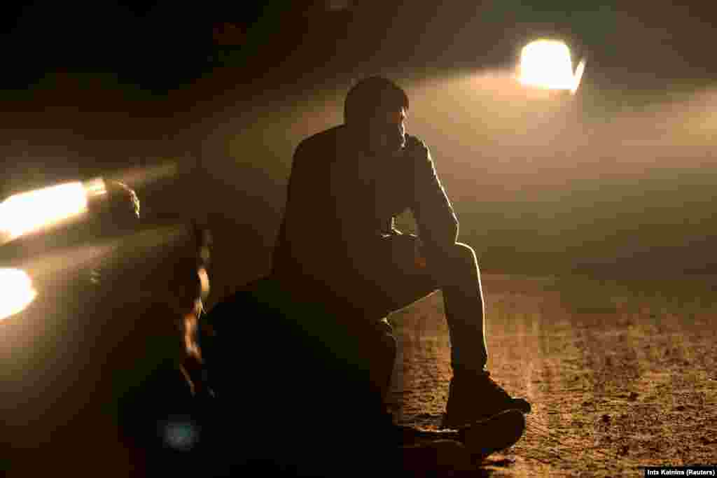 A migrant, who was detained after crossing into Latvia from Belarus, sits next to the border area near Vorzova.&nbsp;