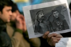 Протест у Болгарії проти будівництва трубопроводу з Росією. Учасник акції тримає колаж, на якому забражено Путіна поруч зі Сталіним. Софія, 2008 рік