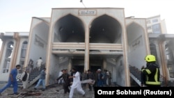 AFGHANISTAN -- Afghan men carry a victim from the site of a suicide attack followed by a clash between Afghan forces and insurgents after an attack on a Shi'ite Muslim mosque in Kabul, August 25, 2017