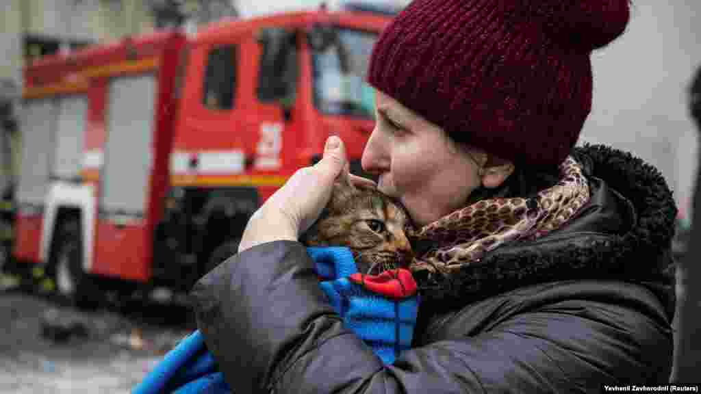 Местная женщина держит свою кошку, спасённую аварийными службами из разрушенного дома&nbsp;