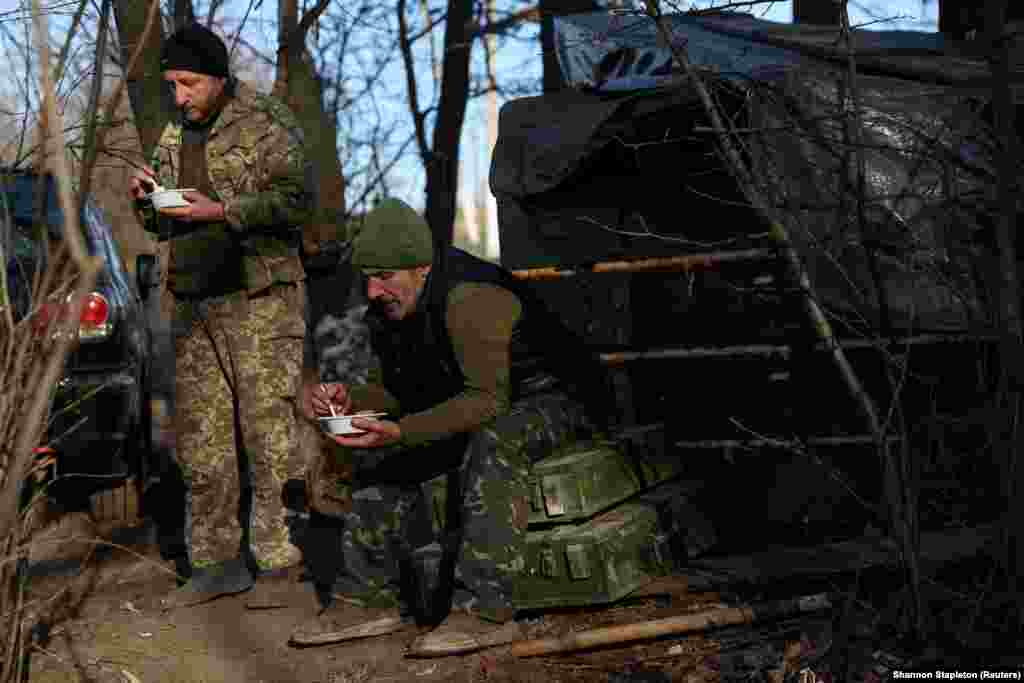 Soldați din Brigada a 10-a de vânători de munte a armatei ucrainene iau prânzul în timpul unei pauze lângă buncărul lor de pe frontul din regiunea Bahmut, la 7 decembrie. &nbsp;