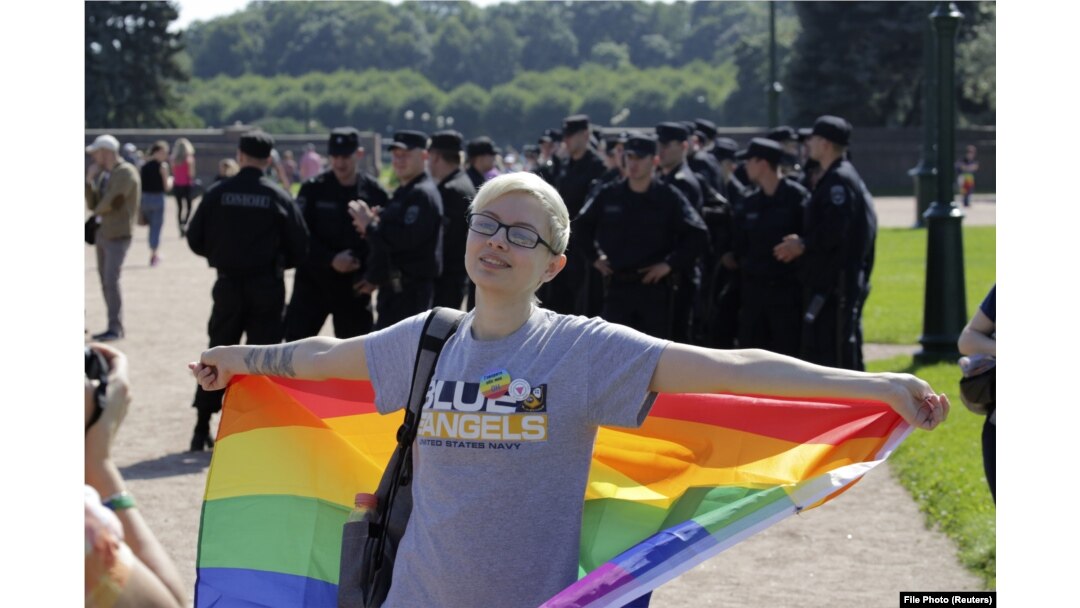 A participant holding a rainbow flag poses for a photo in front of Interior Ministry officers during a LGBT rally in St. Petersburg in 2017.