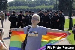 A participant holding a rainbow flag poses for a photo in front of Interior Ministry officers during a LGBT rally in St. Petersburg in 2017.