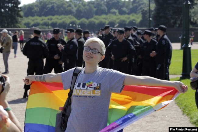 A participant holding a rainbow flag poses for a photo in front of Interior Ministry officers during a LGBT rally in St. Petersburg in 2017.