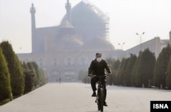 Egy férfi arcmaszkban kerékpározik a szmogtól sújtott Iszfahánban