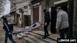 Local residents carry the body of a 20-year-old man killed by Russian shelling in Kherson on January 5.