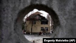 O casă puternic distrusă de bombardamentele rusești este văzută prin gard de beton, Kiev, Ucraina, 14 decembrie 2022