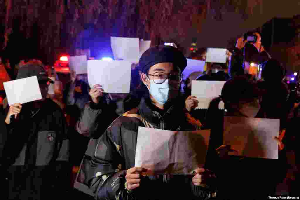 Участники пикета держат белые листы бумаги в знак протеста против коронавирусных ограничений в Китае. 27 ноября 2022 года. Они вышли на акцию после смерти людей при пожаре в Урумчи.&nbsp;Люди в Урумчи, жившие в закрытом на карантин здании, не смогли покинуть его, когда оно загорелось, из-за запертых полицией снаружи дверей, а пожарная техника долго добиралась до места из-за перекрытых дорог