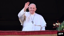 Pope Francis waves to the crowd as he appears at a balcony to deliver his annual Christmas blessing in St. Peter's Square at the Vatican on December 25.