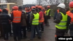 Migranții au trimis la RFE/RL imagini care arată un grup de bărbați - presupuși lucrători tadjici din Mariupol - care își cer salariile de la angajatori. (captură video)