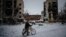 A man pushes his bike next to destroyed residential buildings in Borodyanka, near Kyiv, on December 4.