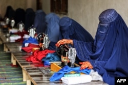 Afghan women, wearing all-encompassing burqas, sew at a workshop in Jalalabad on December 1.