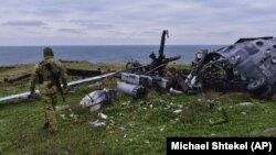 Украинский солдат смотрит на разрушенный российский военный вертолет на острове Змеиный в Черном море, 18 декабря 2022 г. Украинцы восстановили контроль над островом
