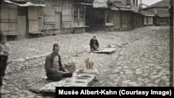 Shitës farërash në kalldrëmin e një rruge në Prishtinë, në Kosovën e sotme, në vitin 1913. 