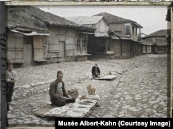 Shitës farërash në kalldrëmin e një rruge në Prishtinë, në Kosovën e sotme, në vitin 1913.