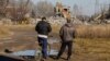 Архивска фотографија: Луѓе ги гледаат работниците како ги острануваат остатоците од урната зграда во Макиивка во Украина