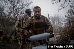 Украинский артиллерист несет снаряд для самоходной гаубицы 2С1 «Гвоздика» на позиции у линии фронта под Бахмутом, 10 декабря 2022 года