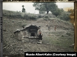 A man poses next to his village’s communal oven in Openica, in what is now North Macedonia, in 1913.