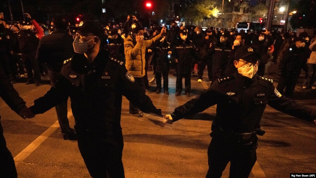 Ofițeri de poliție formează un cordon în jurul protestatarilor. Manifestările din ultimele zile din China sunt fără precedent în regimul lui Xi Jinping.