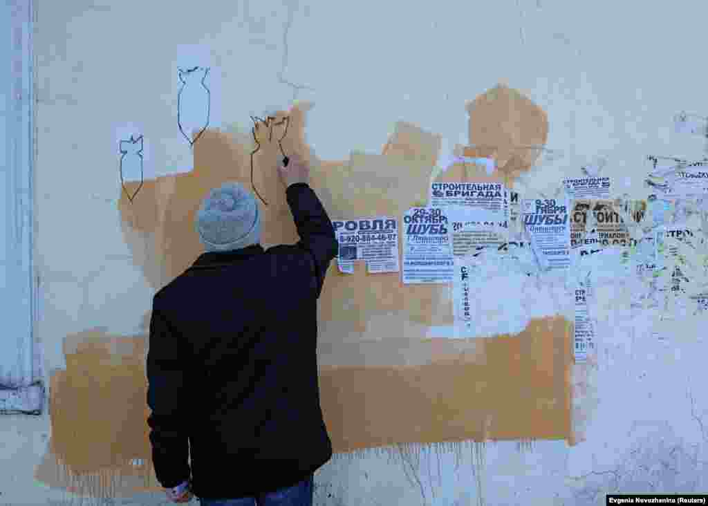 Ovcinnikov desenează pe un zid din Borovsk bombe căzând. Ovcinnikov consideră că activismul său - care include administrarea unei pagini de internet dedicate victimelor terorii politice - este penalizat de autorități din cauza faptului că este în dezacord cu narațiunea preferată de Kremlin, care glorifică URSS și rolul acesteia în înfrângerea Germaniei naziste, trecând sub tăcere cele mai întunecate capitole ale istoriei sovietice.