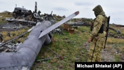 Një ushtar ukrainas e shikon një helikopter rus të rrëzuar afër Detit të Zi, 18 dhjetor 2022.