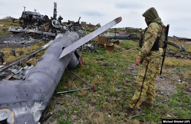 Украинский военный на острове Змеиный возле уничтоженного российского вертолета, 18 декабря 2022 года