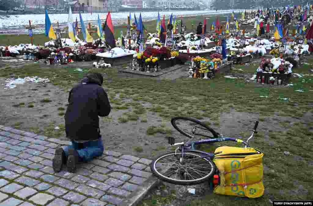 A man prays in front of soldiers&#39; graves on Ukraine&#39;s Day of Dignity and Freedom at the Lychakiv Cemetery in Lviv on November 21.