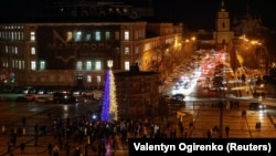 People walk past the Christmas tree on Sofiyska Square in Kyiv on December 19.