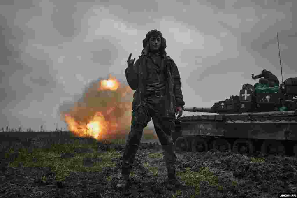 Un soldat ucrainean făcând un gest de triumf în timp ce un tanc rusesc T-80 capturat trage asupra unei poziții inamice în regiunea Donețk.