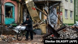 Un localnic trece cu bicicleta pe lângă capcane anti-tanc și ruine, pe o stradă din Bahmut, Donețk, 6 ianuarie.