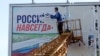 Рабочий отрывает рекламное изображение с надписью «Россия здесь навсегда» в недавно освобожденном украинскими войсками Херсоне, 14 ноября 2022 года