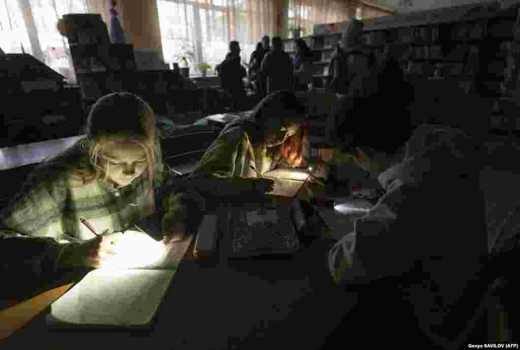 Children use flashlights on their mobile phones during a power outage at a meeting of their literature club in Irpin&#39;s public library on December 23. Located on the ground floor of a nine-story apartment block, the library has become a symbol of a tentative recovery following the devastation of the Russian occupation.