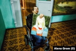 Seryozha, un pacient al spitalului Borodeanka și artist care a învățat să picteze de unul singur, arată camerei o pictură intitulată „Madonna Fără Chip”