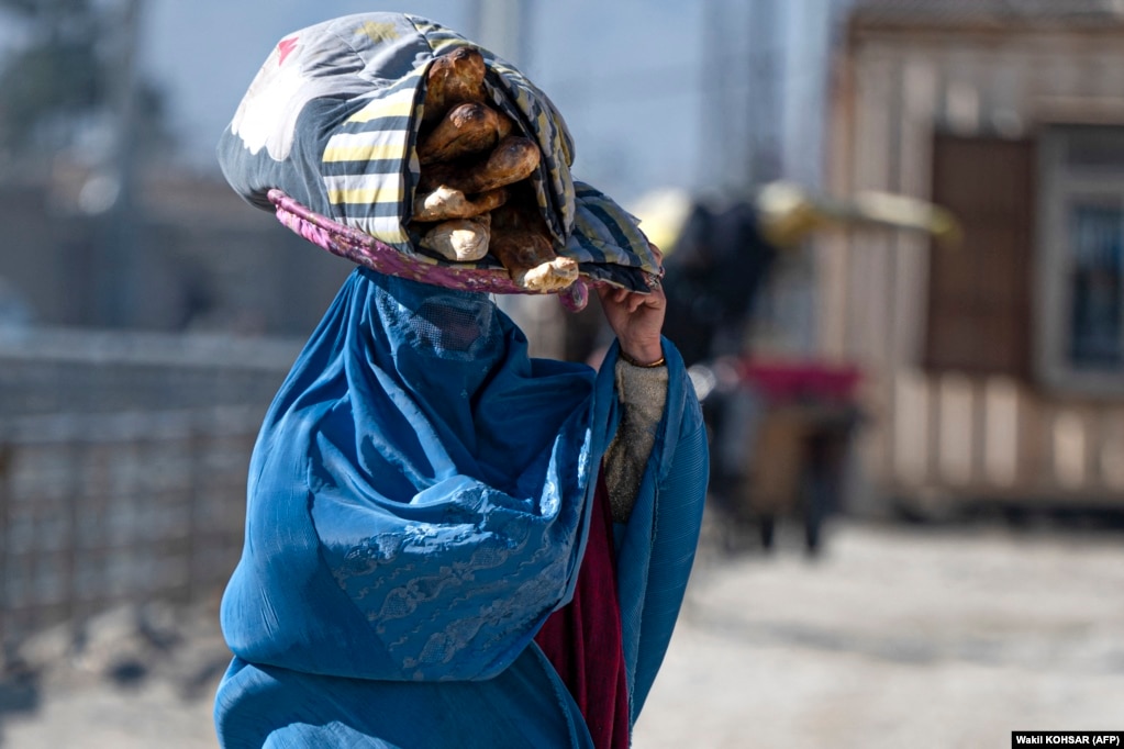 Një grua afgane shihet duke bartur bukën rrugëve të Kabulit.
