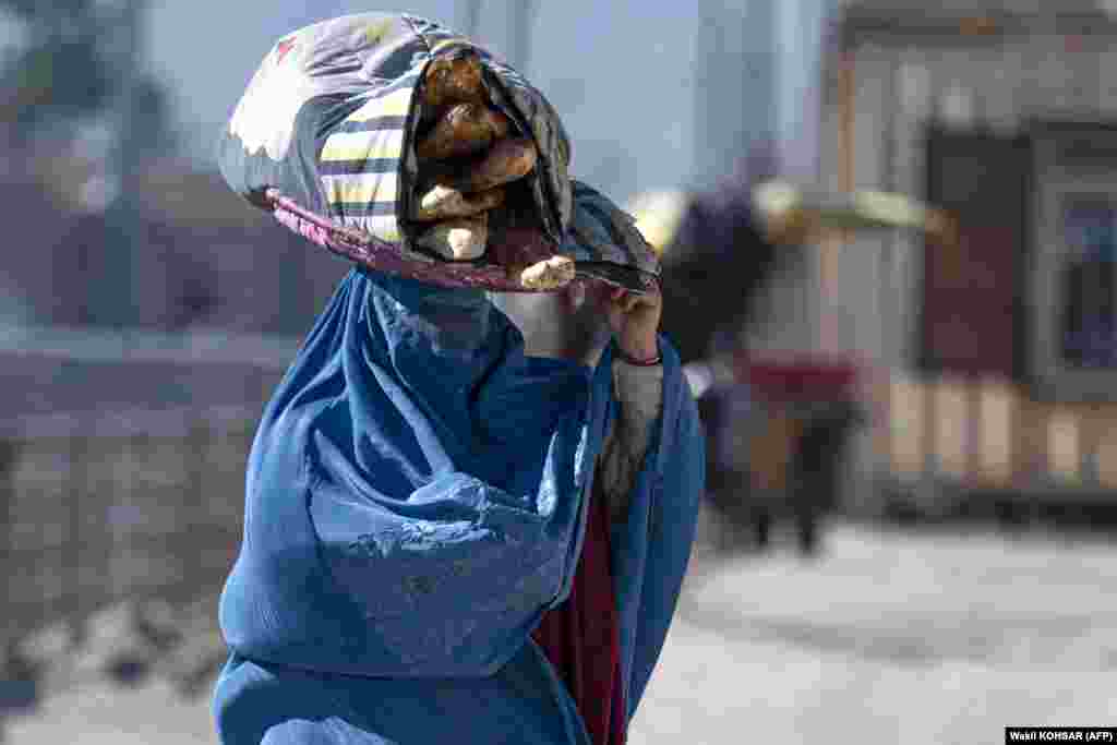 An Afghan woman carries bread on a tray along a street in Kabul.
