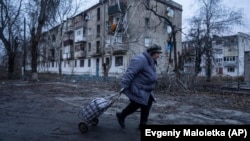 A local woman walks to the distribution point of humanitarian aid in front of housing that was damaged by Russian shelling in Kupyansk, in Ukraine's Kharkiv region, on December 28.