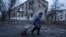A local woman walks to the distribution point of humanitarian aid in front of housing that was damaged by Russian shelling in Kupyansk, in Ukraine's Kharkiv region, on December 28.